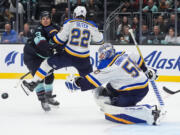 St. Louis Blues goaltender Jordan Binnington (50) looks on as the puck flies out of reach and defenseman Ryan Suter (22) and Seattle Kraken left wing Brandon Tanev, left, collide during the second period of an NHL hockey game Tuesday, Oct. 8, 2024, in Seattle.