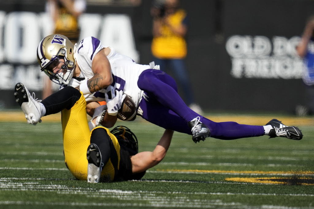 Washington wide receiver Audric Harris (13) is tackled by Iowa defensive back Zach Lutmer after catching a pass during the second half of an NCAA college football game, Saturday, Oct. 12, 2024, in Iowa City, Iowa. Iowa won 40-16.