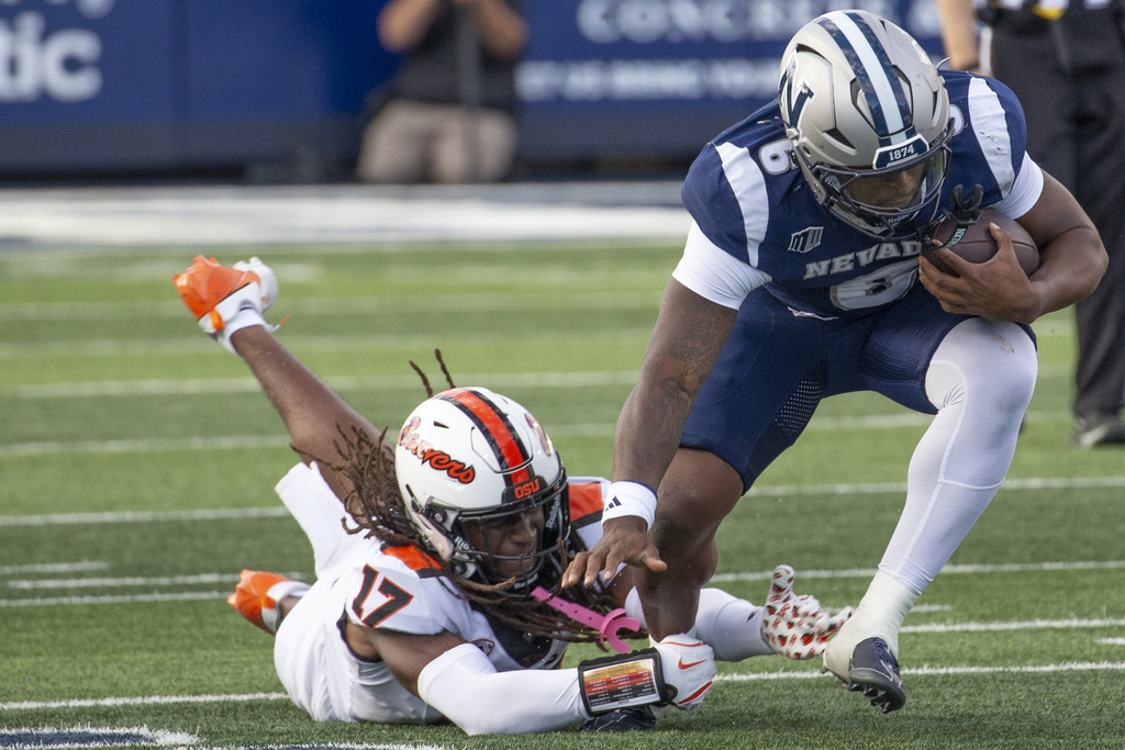 Nevada running back Savion Red (6) is grabbed Oregon State defensive back Skyler Thomas (17) in the first half of an NCAA college football game in Reno, Nev., Saturday, Oct. 12, 2024. (AP Photo/Tom R.