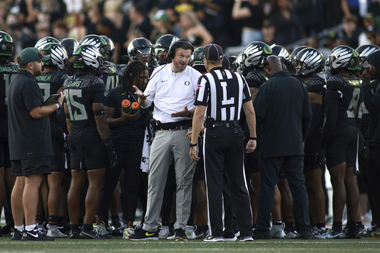 Oregon head coach Dan Lanning, center left, talks with a referee, center right, during an NCAA college football game against Ohio State, Saturday, Oct. 12, 2024, in Eugene, Ore.