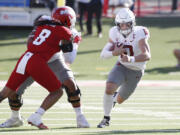 Washington State quarterback John Mateer heads through the line against Fresno State linebacker Tuasivi Nomura during the first half of an NCAA college football game in Fresno, Calif., Saturday, Oct. 12, 2024.