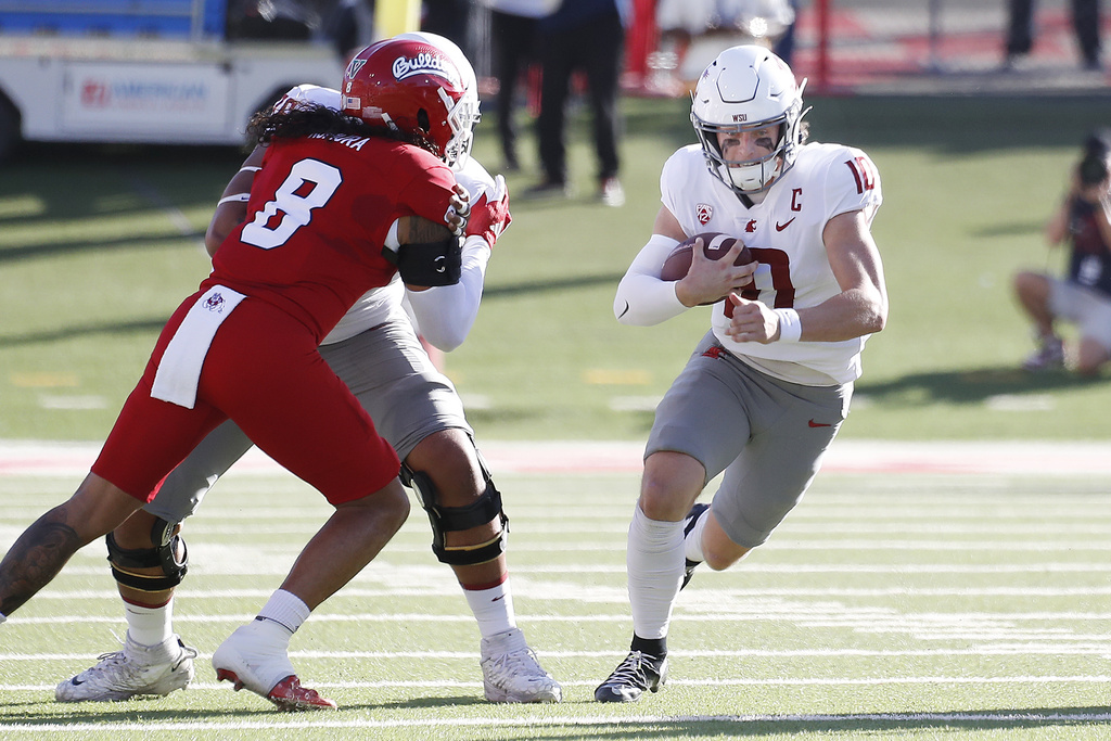 Washington State quarterback John Mateer heads through the line against Fresno State linebacker Tuasivi Nomura during the first half of an NCAA college football game in Fresno, Calif., Saturday, Oct. 12, 2024.