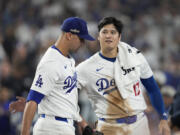 Los Angeles Dodgers pitcher Jack Flaherty, left, is greeted by Shohei Ohtani as he returns to the dugout during the seventh inning in Game 1 of a baseball NL Championship Series against the New York Mets, Sunday, Oct. 13, 2024, in Los Angeles.