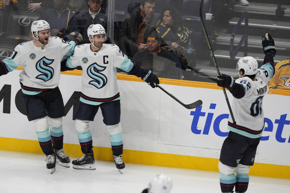 Seattle Kraken right wing Jordan Eberle, center, celebrates his goal with center Shane Wright (51) and defenseman Brandon Montour (62) during the third period of an NHL hockey game against the Nashville Predators, Tuesday, Oct. 15, 2024, in Nashville, Tenn.