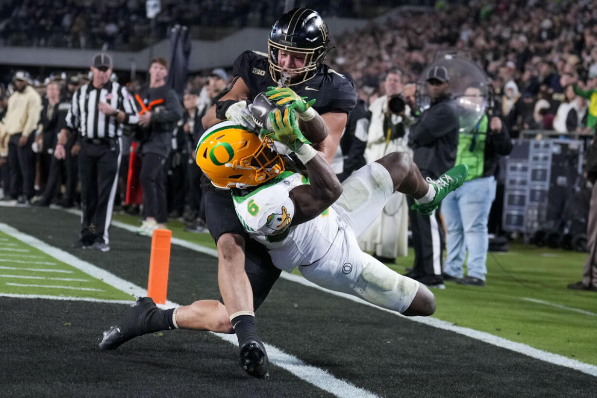 Oregon running back Noah Whittington (6) is forced out of bounds by of Purdue linebacker Yanni Karlaftis, top, after scoring a touchdown during the second half of an NCAA college football game in West Lafayette, Ind., Friday, Oct. 18, 2024.