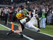 Oregon running back Noah Whittington (6) is forced out of bounds by of Purdue linebacker Yanni Karlaftis, top, after scoring a touchdown during the second half of an NCAA college football game in West Lafayette, Ind., Friday, Oct. 18, 2024.