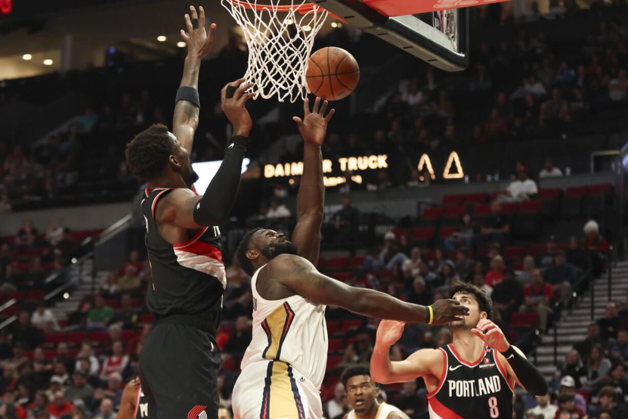 New Orleans Pelicans forward Zion Williamson, center, shoots between Portland Trail Blazers center Deandre Ayton, left, and forward Deni Avdija (8) during the second half of an NBA basketball game Friday, Oct. 25, 2024, in Portland, Ore.