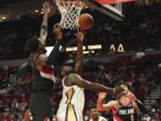 New Orleans Pelicans forward Zion Williamson, center, shoots between Portland Trail Blazers center Deandre Ayton, left, and forward Deni Avdija (8) during the second half of an NBA basketball game Friday, Oct. 25, 2024, in Portland, Ore.