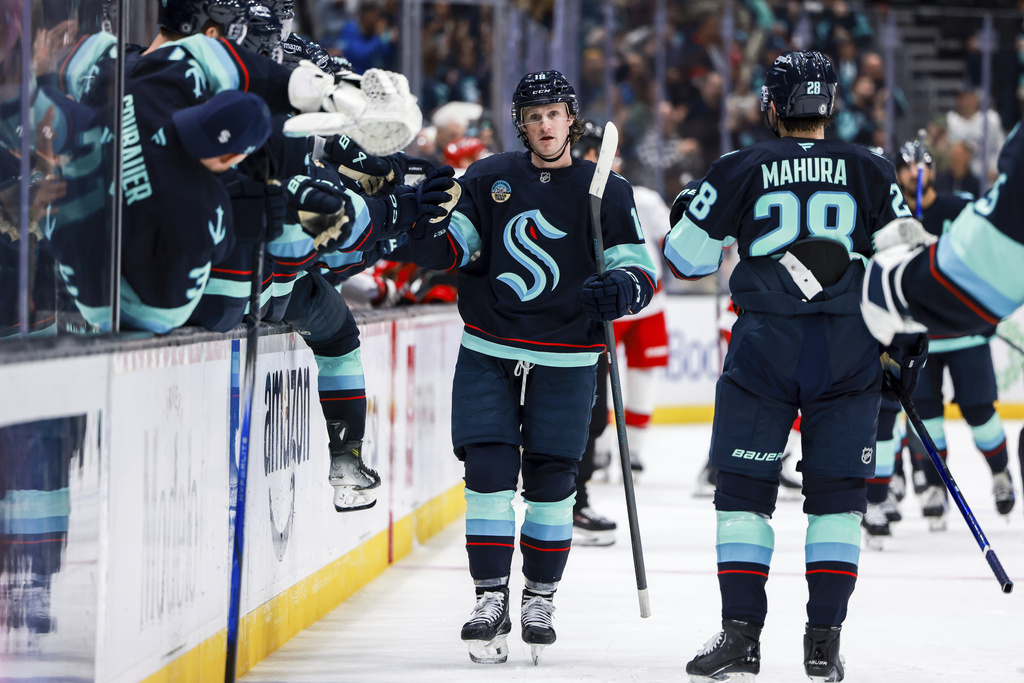 Seattle Kraken left wing Jared McCann, center, celebrates with teammates after his goal during the third period in an NHL hockey game against the Carolina Hurricanes, Saturday, Oct. 26, 2024, in Seattle.