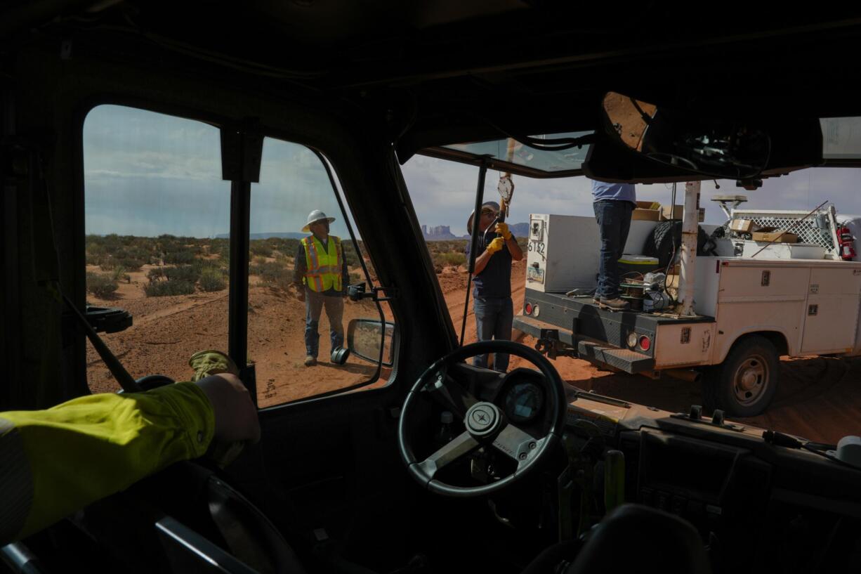 Robert Atene, left, with the Navajo Tribal Utility Authority, supervises as a volunteer crew lifts a power line pole, Tuesday, Oct. 8, 2024, on the Navajo Nation in Halchita, Utah. (AP Photo/Joshua A.