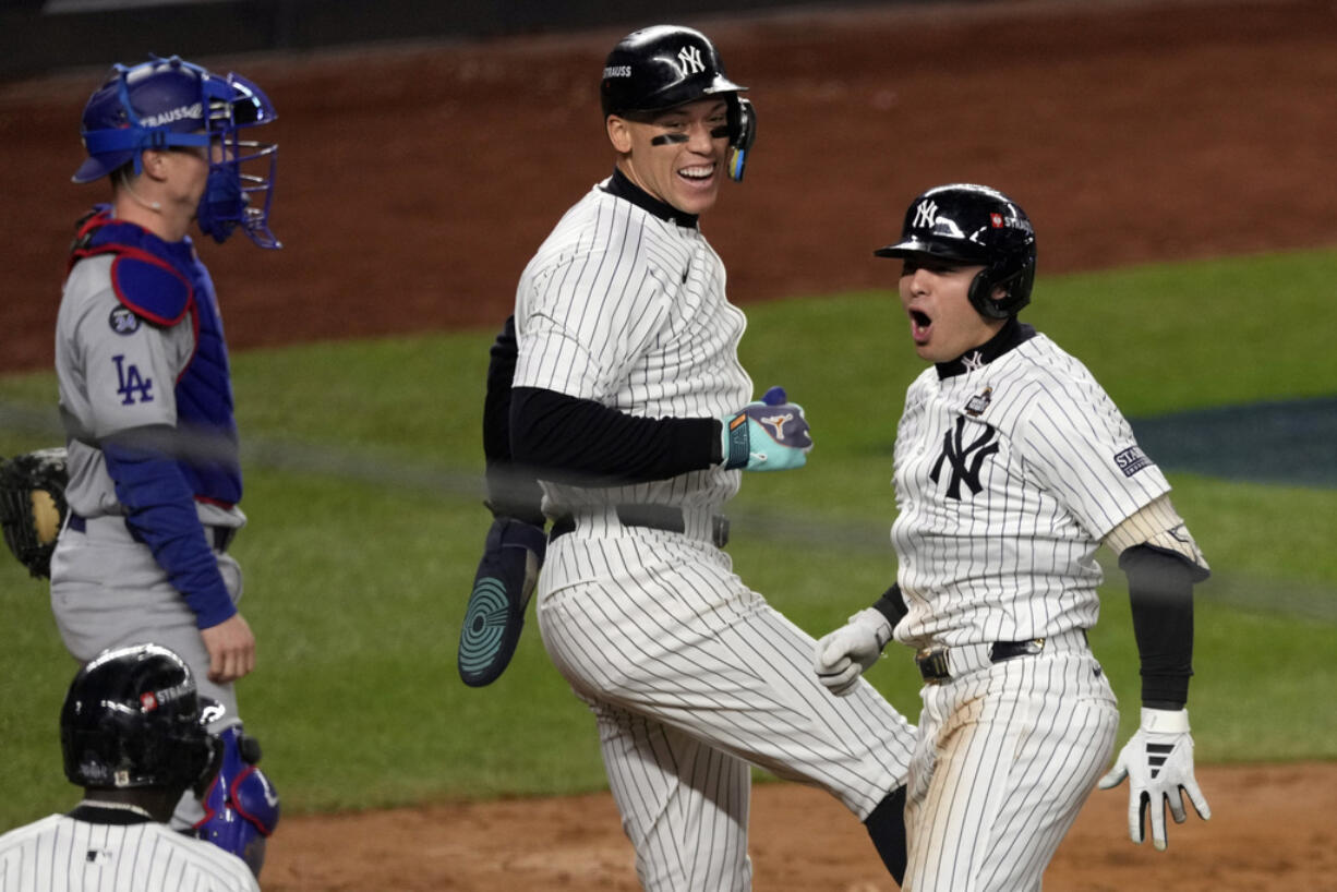 New York Yankees' Anthony Volpe, right, celebrates with Aaron Judge, center, after hitting a grand slam against the Los Angeles Dodgers during the third inning in Game 4 of the baseball World Series, Tuesday, Oct. 29, 2024, in New York.