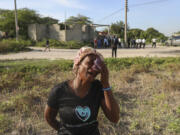 A neighbor cries during the funeral of Jean Louis Jeune Gracien, who was killed during an attack by armed gangs Tuesday in Pont-Sonde, Haiti.