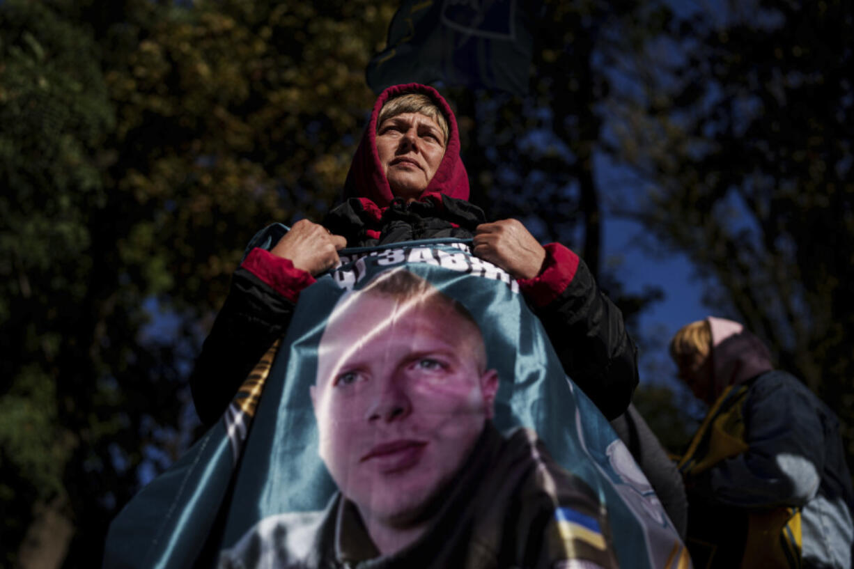 Svetlana holds a flag with a photo of her son Andrii Savchuk, a Ukrainian officer of the 36th marine brigade, during a gathering in support of soldiers who defended Mariupol and are still in Russian captivity after two and half years, in Kyiv, Ukraine, Wednesday, Oct. 9, 2024.