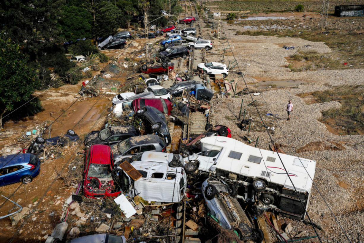 A man stands next to flooded cars piled up in Valencia, Spain, Thursday, Oct. 31, 2024.