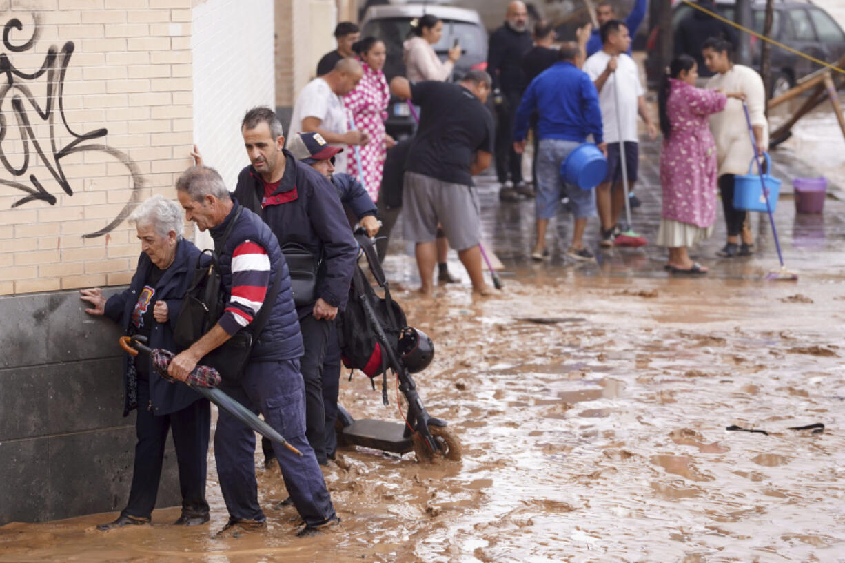 People walk through flooded streets in Valencia, Spain, Wednesday, Oct. 30, 2024.