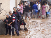 People walk through flooded streets in Valencia, Spain, Wednesday, Oct. 30, 2024.