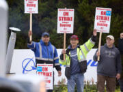 Boeing Machinists Union members Steven Wilson, left, Dave Hendrickson, center,, and Mark Erickson, right, wave to passing traffic while on the picket line at the Renton assembly plant, Friday, Sept. 13, 2024, in Renton, Wash.