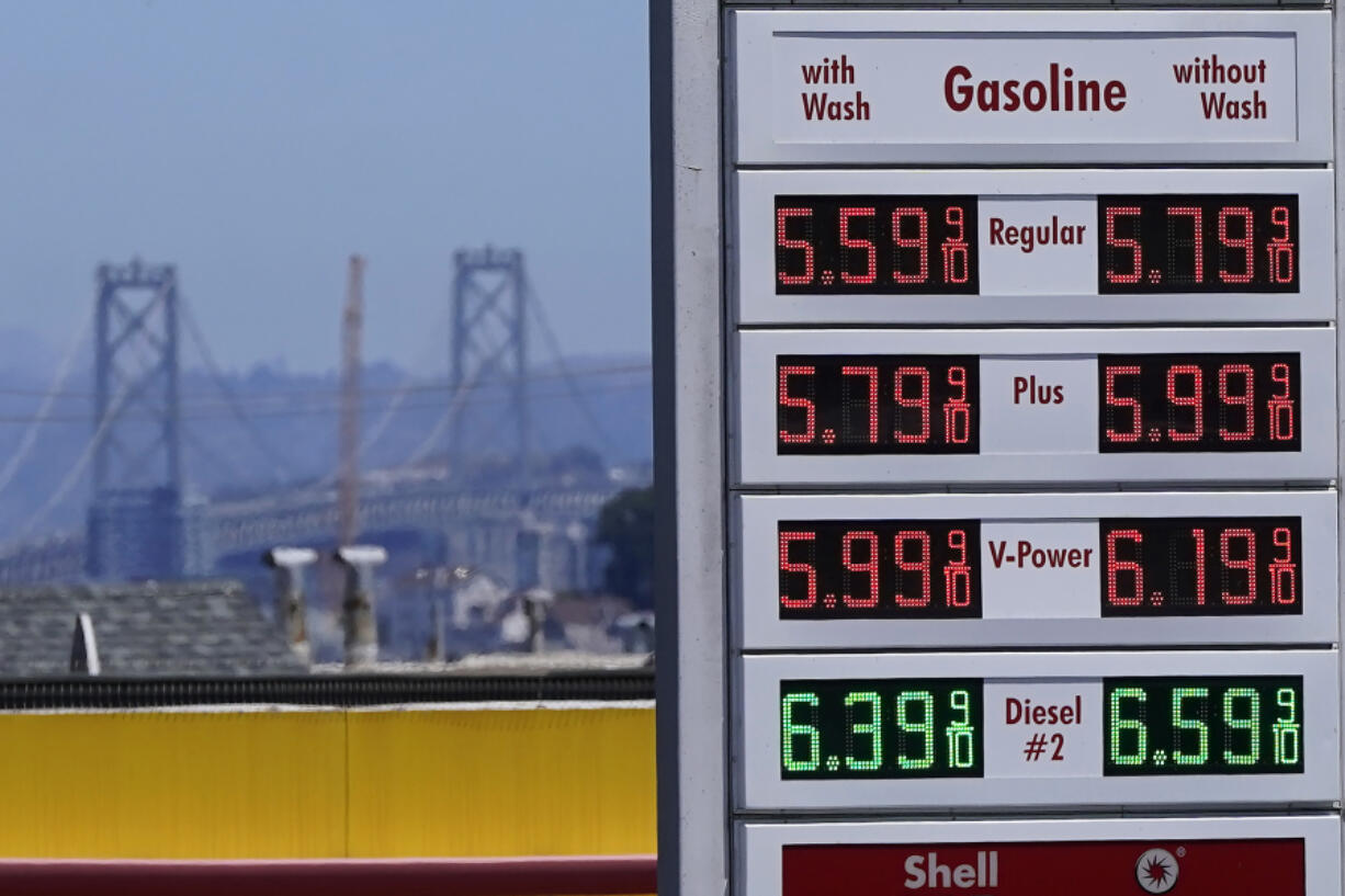 FILE - The San Francisco-Oakland Bay Bridge rises behind the price board of a gas station in San Francisco on July 20, 2022.