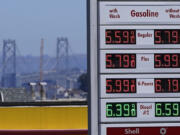 FILE - The San Francisco-Oakland Bay Bridge rises behind the price board of a gas station in San Francisco on July 20, 2022.