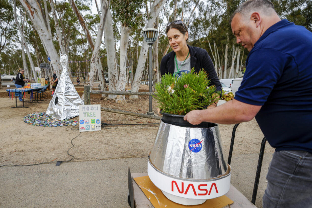 Santiago parent volunteer Stacie Aguesse, left, delivers Monday a small giant sequoia tree from NASA&rsquo;s Artemis I Mission&rsquo;s tree seeds that traveled around the moon twice, as NASA scientists, JPL engineers, U.S. Forest Service representatives and teachers join Santiago STEAM Magnet Elementary School students at a ceremony to plant it after the school was honored in the spring of 2024 to become NASA Moon Tree Stewards in Lake Forest, Calif.