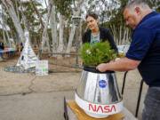 Santiago parent volunteer Stacie Aguesse, left, delivers Monday a small giant sequoia tree from NASA&rsquo;s Artemis I Mission&rsquo;s tree seeds that traveled around the moon twice, as NASA scientists, JPL engineers, U.S. Forest Service representatives and teachers join Santiago STEAM Magnet Elementary School students at a ceremony to plant it after the school was honored in the spring of 2024 to become NASA Moon Tree Stewards in Lake Forest, Calif.