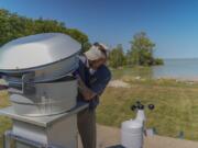 David Kennedy, an associate professor of medicine at the University of Toledo, replaces an air filter inside of a monitoring station near Lake Erie, Thursday, Sept. 5, 2024, in Oregon, Ohio. (AP Photo/Joshua A.