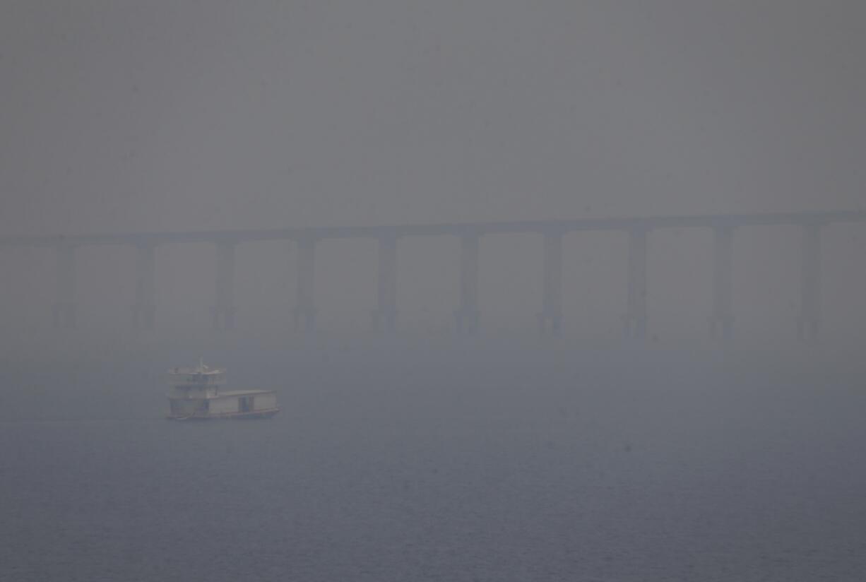 FILE - A boat navigates the Negro River amid smoke from wildfires in Manaus, Amazonas state, Brazil, Aug. 27, 2024.