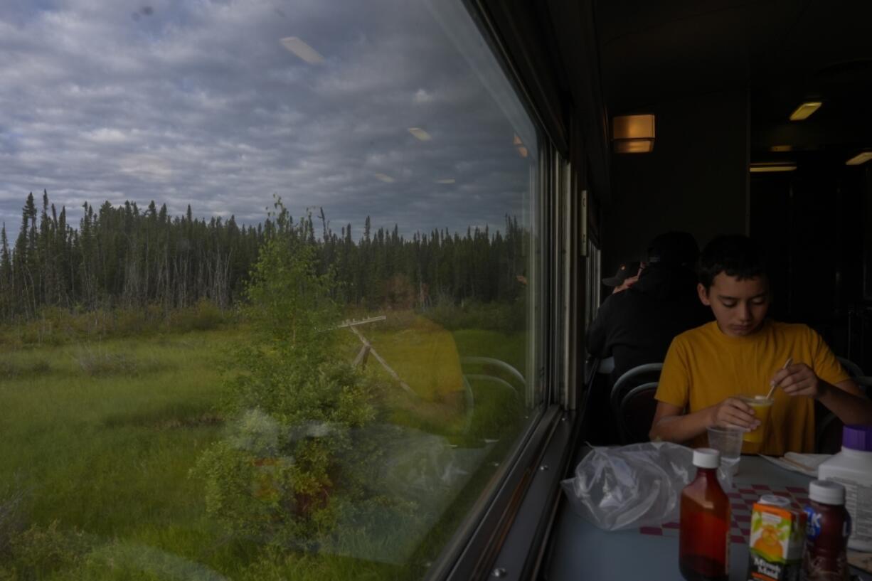 A passenger eats breakfast as a train travels Friday, Aug. 9, 2024, near Ilford, Manitoba. (AP Photo/Joshua A.