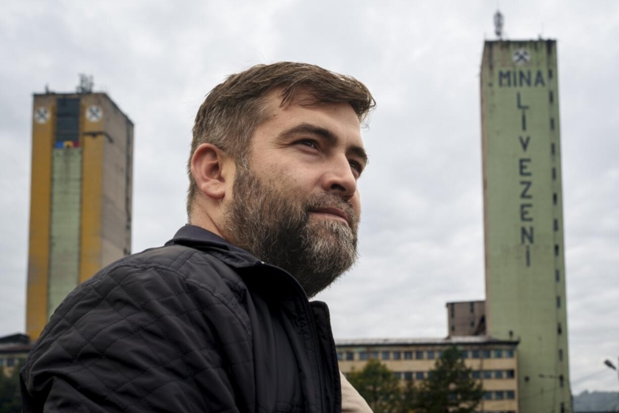 Sebastian Tirintica stands backdropped by buildings at the entrance of the Livezeni coal mine, his former workplace, in Petrosani, southern Romania, Friday, Oct. 11, 2024.