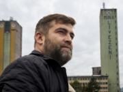 Sebastian Tirintica stands backdropped by buildings at the entrance of the Livezeni coal mine, his former workplace, in Petrosani, southern Romania, Friday, Oct. 11, 2024.