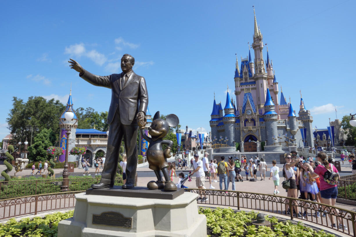 FILE - Guests pass a statue of Walt Disney and Mickey Mouse in the Magic Kingdom at Walt Disney World on July 14, 2023, in Lake Buena Vista, Fla.