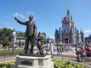 FILE - Guests pass a statue of Walt Disney and Mickey Mouse in the Magic Kingdom at Walt Disney World on July 14, 2023, in Lake Buena Vista, Fla.