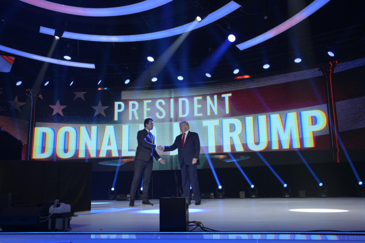 FILE - Former President Donald Trump, right, shakes hands with Turning Point CEO Charlie Kirk before speaking during the Turning Point USA Student Action Summit, Saturday, July 23, 2022, in Tampa, Fla. (AP Photo/Phelan M.