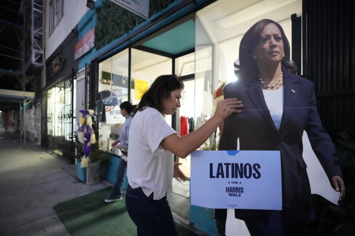 Emiliana Guereca, founder and president of the Women&rsquo;s March Foundation, adjusts a placard with the image of Democratic presidential nominee Vice President Kamala Harris outside a phone bank in Los Angeles on Tuesday, Oct. 15, 2024.