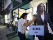 Emiliana Guereca, founder and president of the Women&rsquo;s March Foundation, adjusts a placard with the image of Democratic presidential nominee Vice President Kamala Harris outside a phone bank in Los Angeles on Tuesday, Oct. 15, 2024.