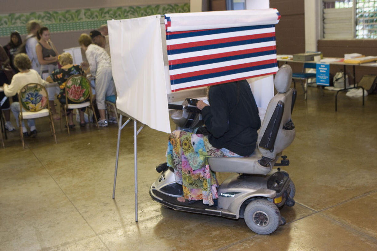 FILE - A woman in a motorized wheelchair casts her vote at the Waikiki Community Center in Honolulu, on Tuesday, Nov. 4 2008.