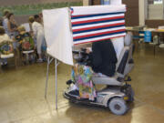 FILE - A woman in a motorized wheelchair casts her vote at the Waikiki Community Center in Honolulu, on Tuesday, Nov. 4 2008.