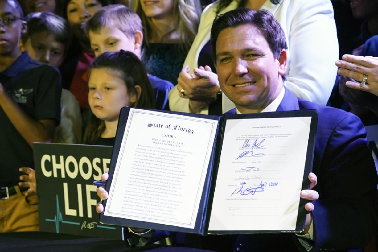 FILE - Florida Gov. Ron DeSantis holds up a 15-week abortion ban law after signing it on April 14, 2022, in Kissimmee, Fla.