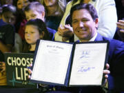 FILE - Florida Gov. Ron DeSantis holds up a 15-week abortion ban law after signing it on April 14, 2022, in Kissimmee, Fla.