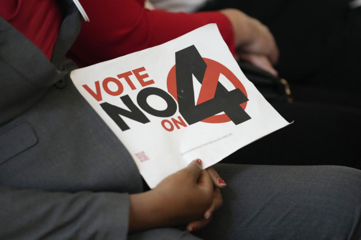 A person in the audience holds a sign against Amendment 4 which would protect access to abortion as Florida Gov. Ron DeSantis speaks during a news conference with Florida Physicians Against Amendment 4 Monday, Oct. 21, 2024, in Coral Gables, Fla.