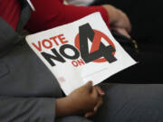 A person in the audience holds a sign against Amendment 4 which would protect access to abortion as Florida Gov. Ron DeSantis speaks during a news conference with Florida Physicians Against Amendment 4 Monday, Oct. 21, 2024, in Coral Gables, Fla.