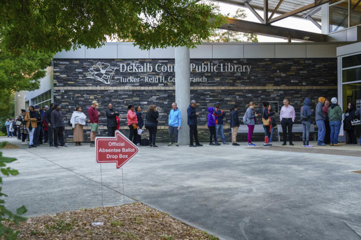 People line up around the building at the Tucker-Reid H. Cofer branch of the Dekalb County Public Library on the first day of early voting, Tuesday, Oct. 15, 2024 in Tucker, Ga.