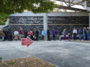 People line up around the building at the Tucker-Reid H. Cofer branch of the Dekalb County Public Library on the first day of early voting, Tuesday, Oct. 15, 2024 in Tucker, Ga.