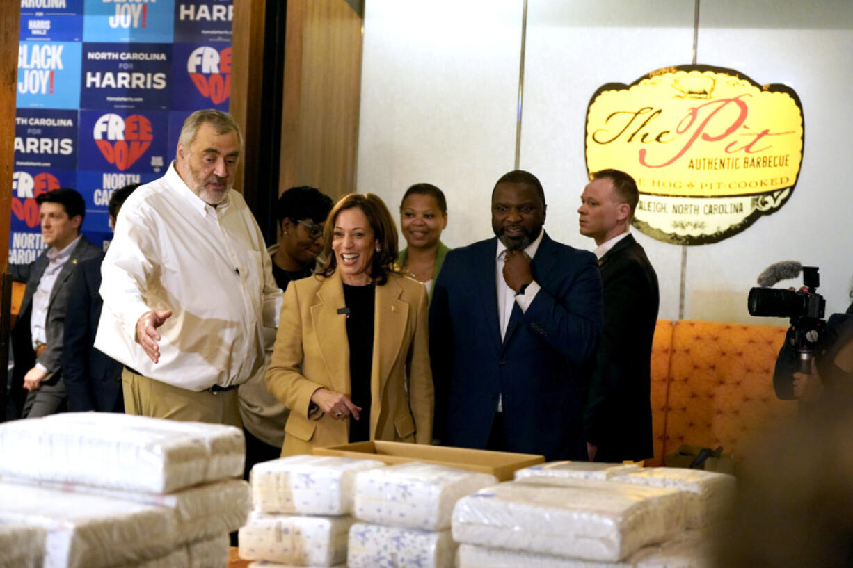 Greg Hatem, owner of The Pit Authentic Barbecue, from left, shows Democratic presidential nominee Vice President Kamala Harris diapers and supplies as visits the restaurant to learn about their relief efforts for Hurricane Helene, in Raleigh, N.C., Saturday.