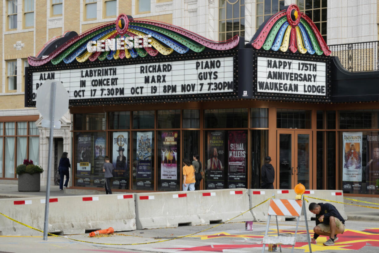 People walk past a theatre in Waukegan, Ill., Saturday, Sept. 28, 2024. (AP Photo/Nam Y.