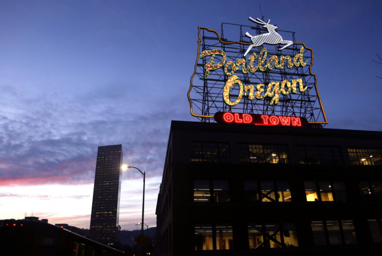 FILE - The &ldquo;Portland, Oregon&rdquo; sign is illuminated in with the Wells Fargo Center building in the background in downtown Portland, Ore., Jan. 27, 2015.