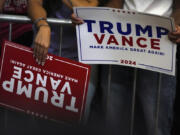 Supporters hold signs as they arrive before Republican presidential nominee former President Donald Trump at a campaign rally at Minges Coliseum, Monday, Oct. 21, 2024, in Greenville, N.C.