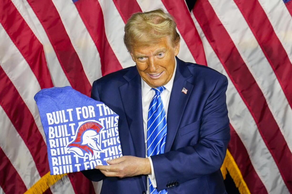 Republican presidential nominee former President Donald Trump shows off a t-shirt given to him by students at a campaign event Tuesday, Oct. 1, 2024, at Discovery World in Milwaukee.