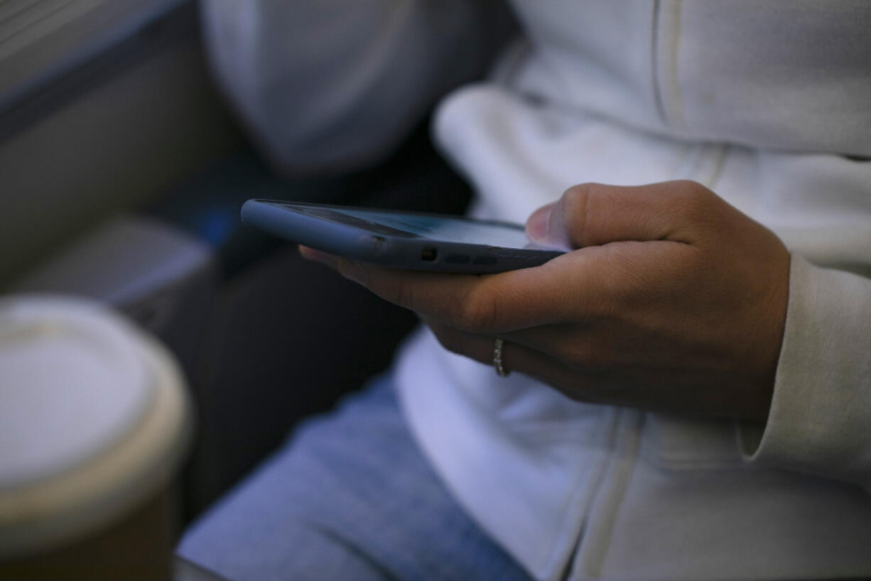 FILE - A woman looks at a hand held device on a train in New Jersey on May 18, 2021.