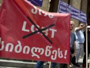 FILE - Georgian far right parties and their supporters hold a banner that reads: &ldquo;No to LGBT darkness,&rdquo; in front of the parliament during a rally against Pride Week in Tbilisi, Georgia, on July 2, 2022.